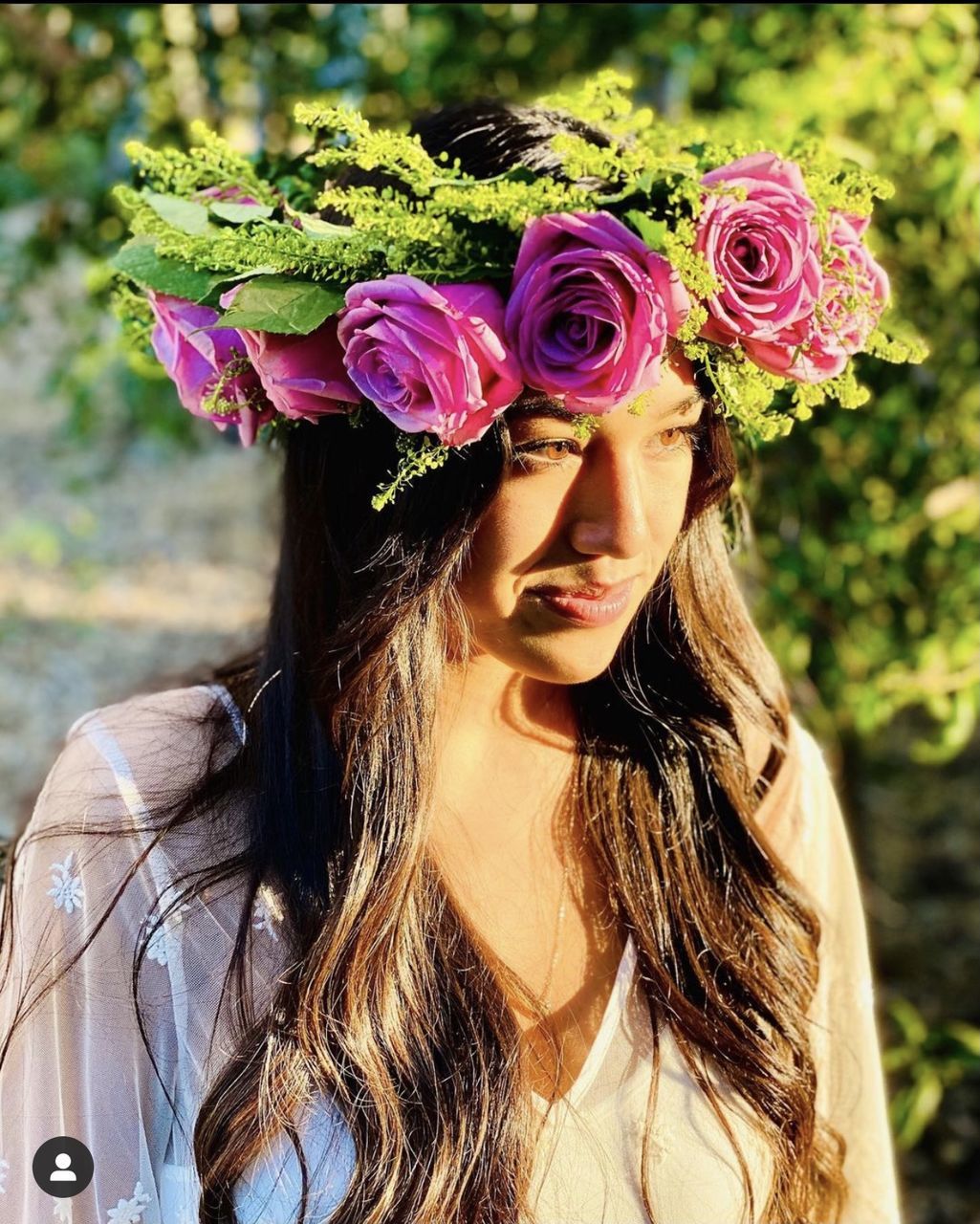 flower, flowering plant, plant, one person, long hair, women, nature, portrait, hairstyle, adult, young adult, beauty in nature, headshot, clothing, rose, pink, outdoors, fashion, brown hair, day, spring, front view, lifestyles, focus on foreground, female, sunlight, freshness, leisure activity, close-up, looking at camera, looking, smiling, person, emotion, dress, fragility, flower arrangement