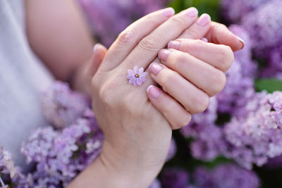 Beautiful woman hands with french manicure over lilac flowers close up. beauty procedure