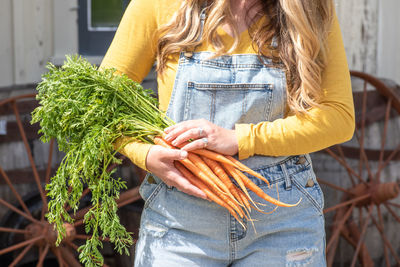 Midsection of woman holding carrots