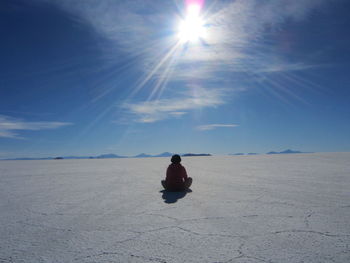 Woman sitting against blue sky at desert