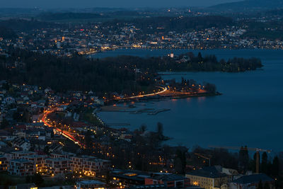 High angle view of illuminated city by sea at night