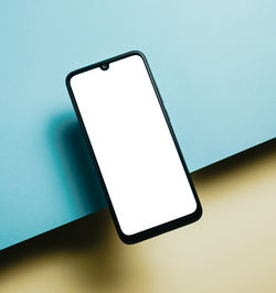Close-up of mobile phone against blue background