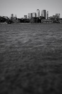 Surface level of calm sea with buildings in background