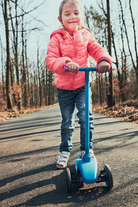 Full length of cute girl standing on scooter in forest