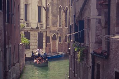 People on boat in canal amidst buildings