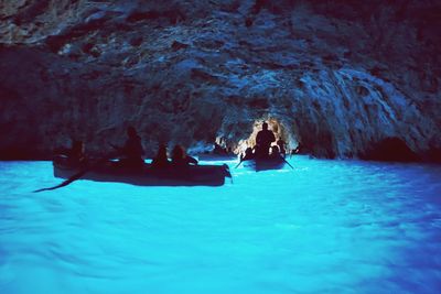 Silhouette people sailing boats on sea in cave