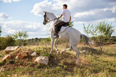 Men riding horse on field against sky