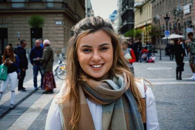 Portrait of smiling young woman standing on street in city