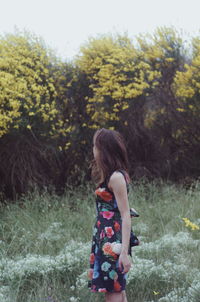 Rear view of woman standing on field against trees