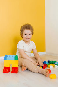 Child is playing with colorful cubes at the table. kid has fun and builds from bright construction 