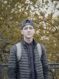 Portrait of young man standing against trees in forest