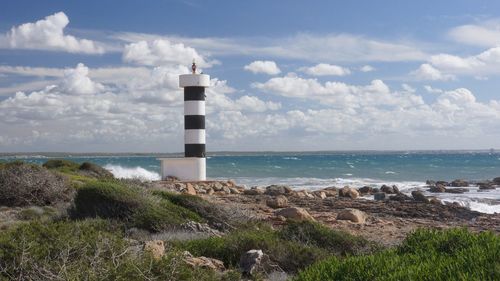 Lighthouse by sea against sky