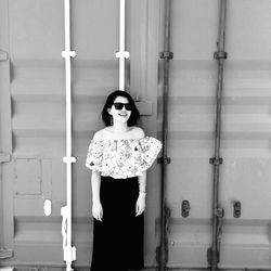 Happy young woman standing against cargo container