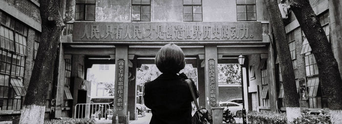 Rear view of woman standing by old building