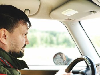 Side view of man driving car