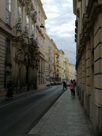 People walking on footpath amidst buildings in city