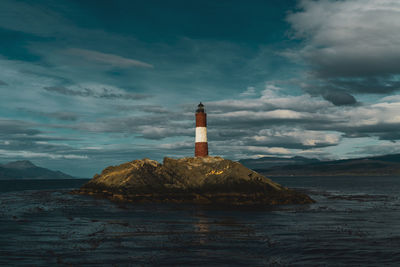 Lighthouse by sea against sky