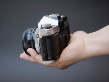 Close-up of hand holding camera over black background