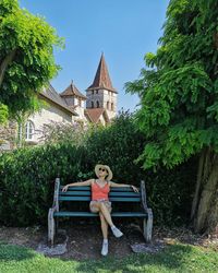 Woman sitting on seat against building