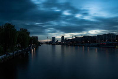 Scenic view of river by buildings against sky at dusk