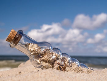 Close-up of bottle on beach against sky