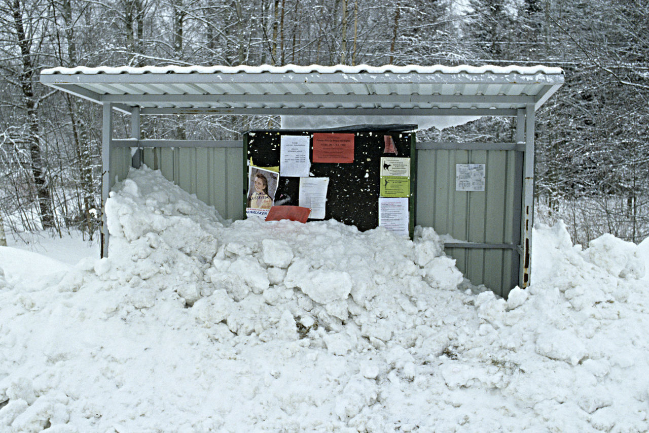 A bus stop shelter full of snow