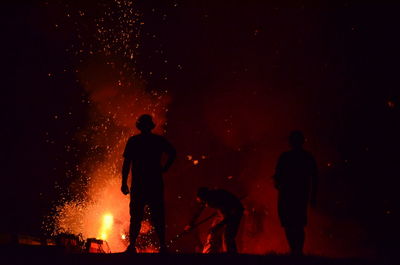 Silhouette people standing against fireworks