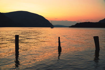 Silhouette wooden post in sea against sky during sunset