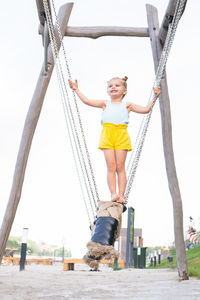 Portrait of young woman swinging at playground