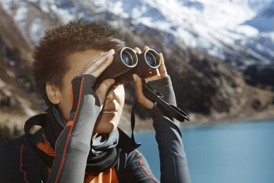 Portrait of man holding sunglasses in sea against mountains