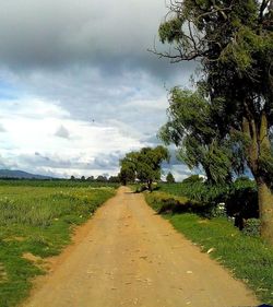 Road amidst field against sky