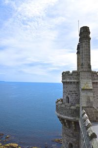 View of tower by sea against sky