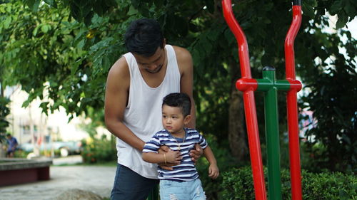 Father and son playing in park against trees