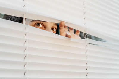 Portrait of young woman looking through window