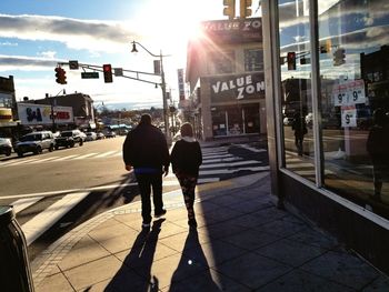 Rear view of men walking on sidewalk in city