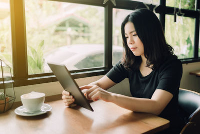 Young woman looking at camera while sitting on table