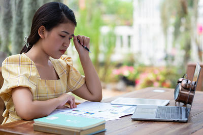 Young woman using mobile phone while sitting on table