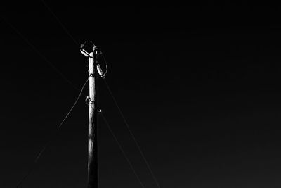 Low angle view of electricity pylon against clear sky at night