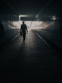 Rear view of man walking on footpath in tunnel