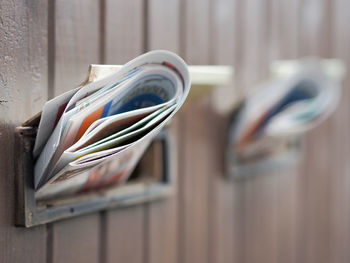 Close-up of folded newspapers in mail slots of closed door