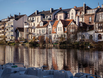 Buildings by river against sky in city