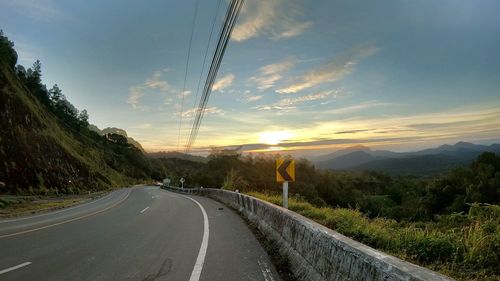 Road amidst plants against sky during sunset