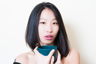 Portrait of young woman against white background