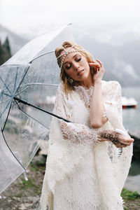 A tender sensual young woman bride in a fashionable wedding dress is standing in the rain in nature