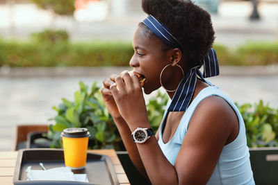 Cute african woman having lunch outdoors in city cafe