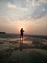 Silhouette of man standing on beach during sunset