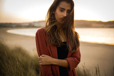 Young woman standing against sky during sunset