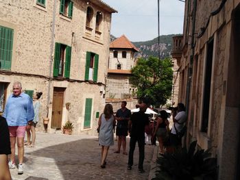 Rear view of people walking on alley amidst buildings