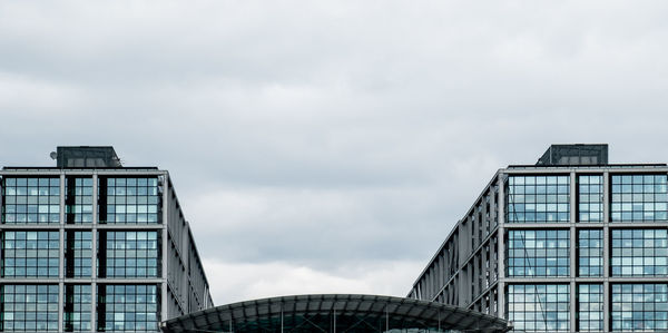 Low angle view of modern buildings against cloudy sky in city