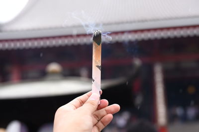 Close-up of hand holding burning incense